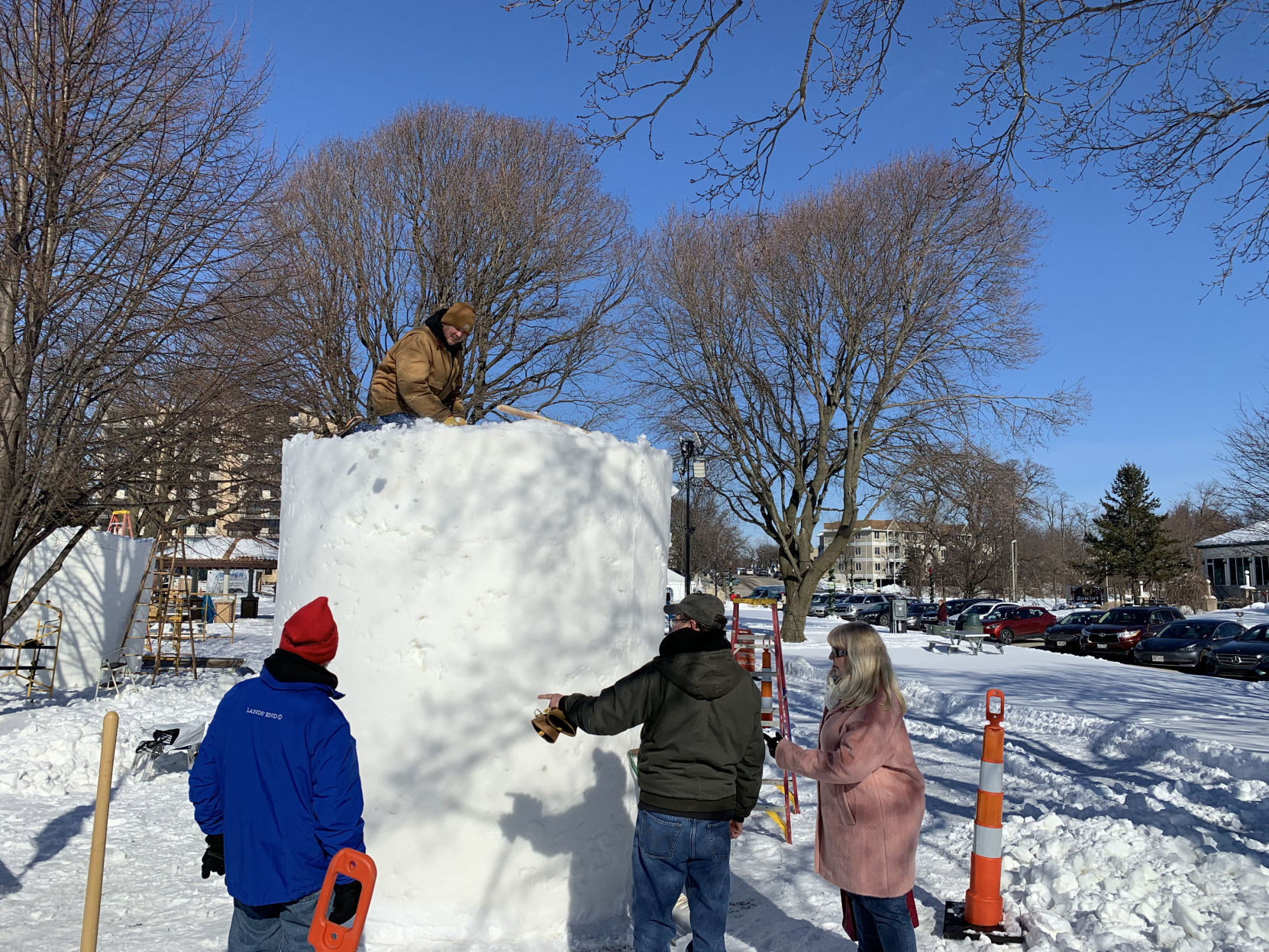 A snow sculpting team begins to work on their sculpture, as spectators watch them work